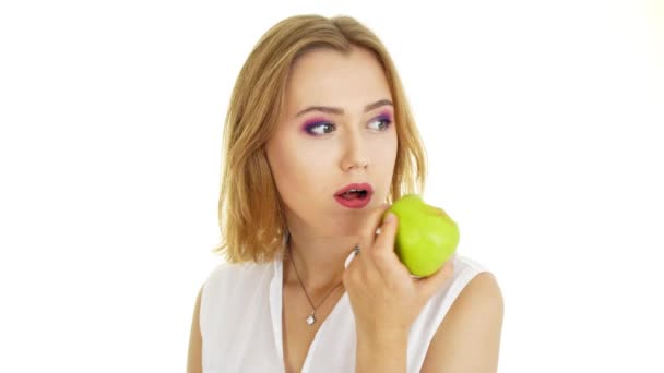 Een vrouw eet een appel. Mooi meisje op een witte achtergrond. — Stockvideo