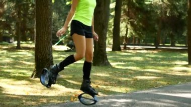 Genç güzel kız parkta spor yapıyor. Bir kadın fitness için özel ayakkabıları atlar.