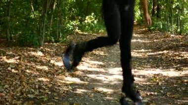 Genç güzel kız parkta spor yapıyor. Bir kadın fitness için özel ayakkabıları atlar.