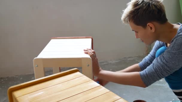 Ein Mädchen bemalt einen Stuhl. Reparatur in der Wohnung mit eigenen Händen. — Stockvideo
