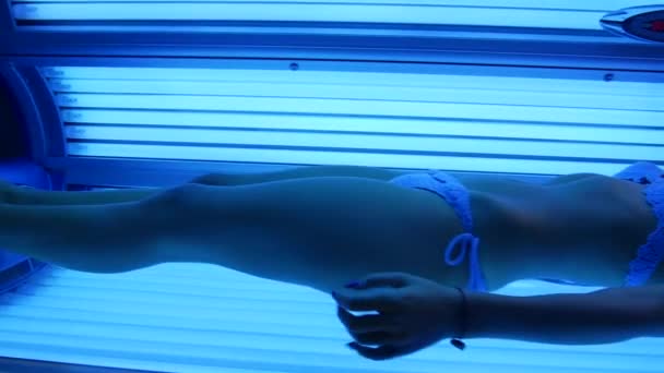 La chica está en el solarium. Joven mujer sexy en bikini tomando el sol . — Vídeo de stock