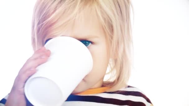 Ребенок пьет напиток из бумажной чашки. Видео на светлом фоне . — стоковое видео