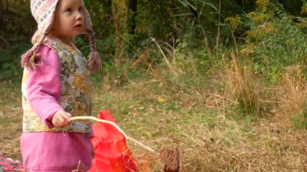 Malá holčička se připravuje chléb na hranici. Dítě k ohni v kampani. — Stock video