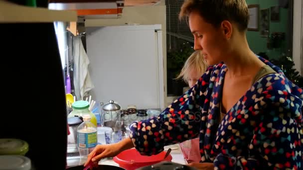 Mamá e hija están preparando comida en la cocina. El apartamento habitual de la gente común . — Vídeo de stock