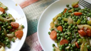 Yeşil bezelye ve havuç güveç. Masada iki porsiyon. Klibin sonunda, kamerayı masanın üzerine çiçek için transfer edilir.