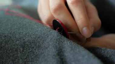 Terzi bir düğme onun giysilerini diker. İğne işi ve küçük giyim onarım