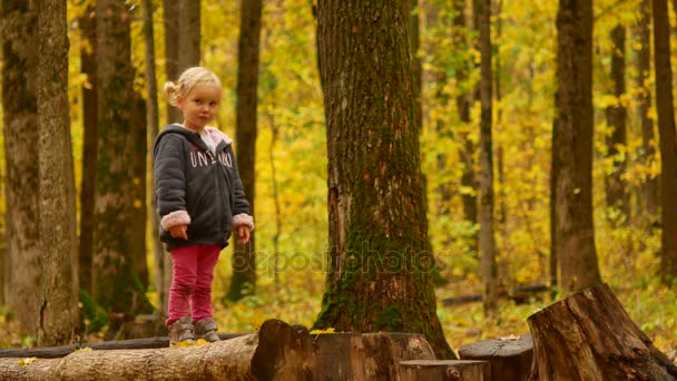Dziecko w lesie jesienią. Dziewczyna jest skakanie z konopi na pniu. — Wideo stockowe