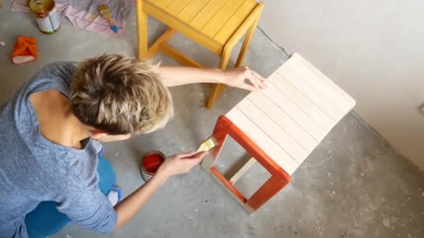 Ein Mädchen bemalt einen Stuhl. Reparatur in der Wohnung mit eigenen Händen. — Stockvideo
