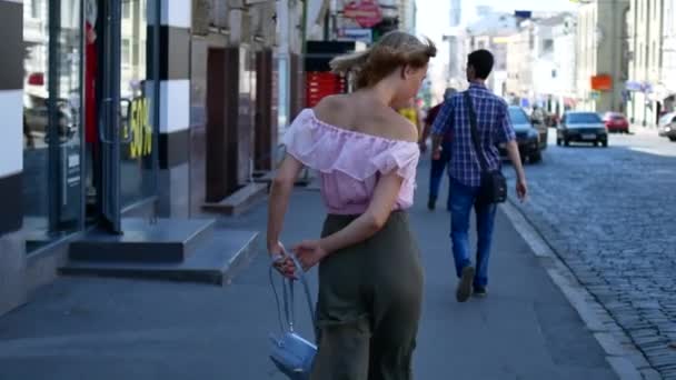 Uma menina alegre corre pela rua da cidade. Uma jovem está girando no córrego da cidade — Vídeo de Stock