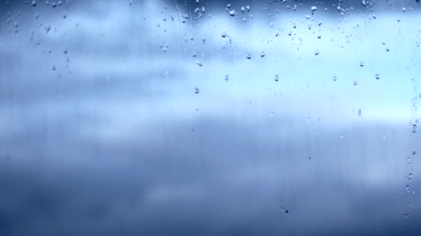 Lluvia cae en la ventana. Fuera de la ventana se puede ver cómo las nubes flotan en el desenfoque — Vídeos de Stock