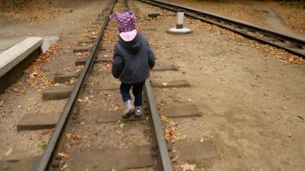 Ένα κοριτσάκι είναι το περπάτημα πάνω σε ράγες. Φθινοπωρινό δάσος. — Αρχείο Βίντεο