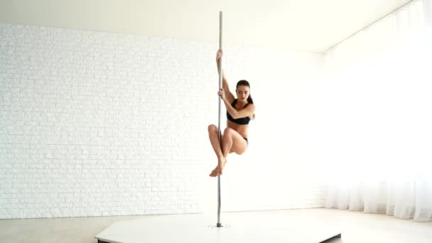Vacker atletisk kvinna utför övningar på en pylon. Flickan är engagerad i poledance — Stockvideo