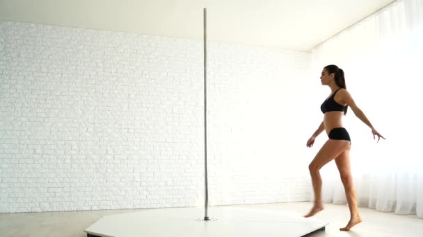 Hermosa mujer atlética realiza ejercicios en un pilón. La chica se dedica a la danza del poste — Vídeos de Stock