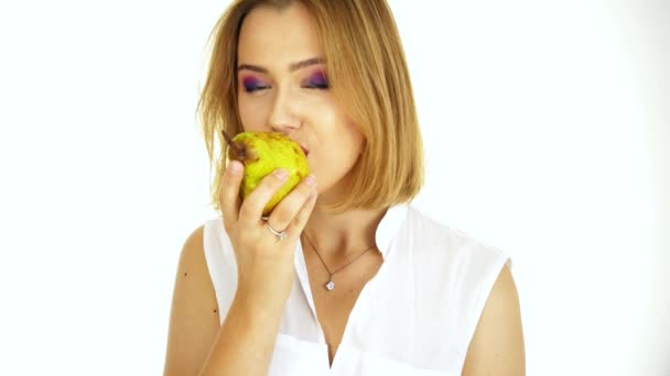 Une jeune femme mange une bouchée de poire. Vidéo sur fond blanc — Video