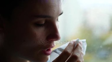 Bir kadın bir burun akıntısı var. Genç bir kız onun yağmur bir pencere oturuyor dışında. Depresyon