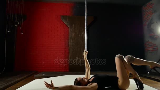Een heel sexy en langbenige meisje dansen in de buurt van de paal. Vrouwelijke poledancer in donkere verlichting — Stockvideo