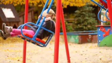 İki çocuk bir salıncağa binmek. Salıncak ile sonbahar park ve çocuk oyun alanı.