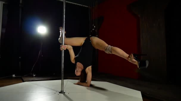 Una chica muy sexy y de piernas largas baila cerca del poste. Poledancer femenino en luces oscuras — Vídeos de Stock