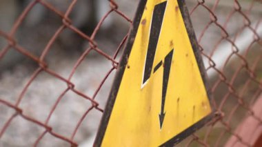 Elektrik tehlikesi uyarı işareti. Enerji santrali çitin üzerine işaret