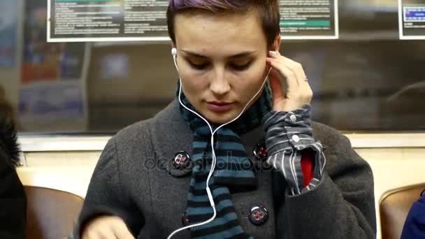 Dívka poslouchá hudbu nebo hodinky video o smartphone ve voze metra — Stock video