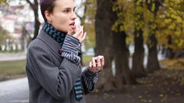 Het meisje zet de crème op haar lippen. Een vrouw in de stad — Stockvideo