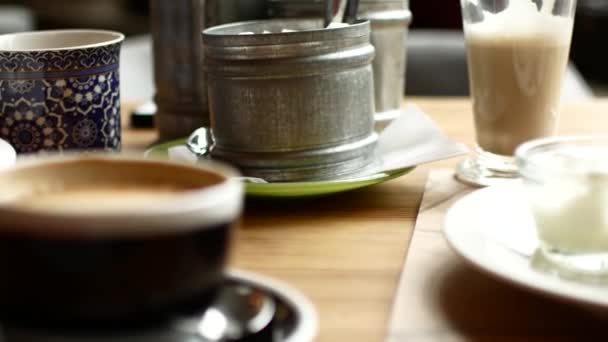 Чашки с кофе и другие продукты питания на столе в ресторане — стоковое видео