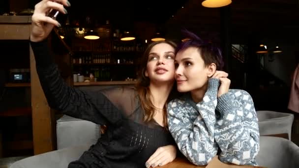 Две девушки делают селфи в ресторане. Женщин фотографируют в кафе за столом — стоковое видео