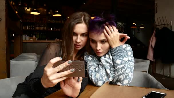 Deux copines font des selfies dans un restaurant. Les femmes sont photographiées dans un café à la table — Video