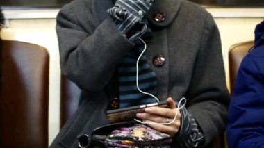 Bir kız müzik dinliyor ya da metro arabanın içinde bir akıllı telefon videoda saatler