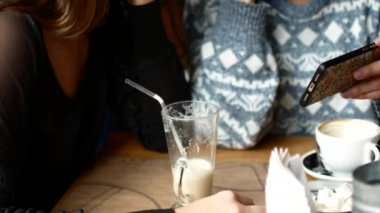 İki arkadaş bir kafede smartphone ve gülmek videoyu izleyin. Kadın kahve kahve evde içki.