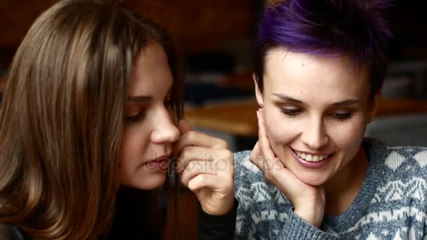 Dois amigos em um café assistir vídeo no smartphone e rir. Mulheres bebem café na casa de café — Vídeo de Stock