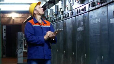 İşçi Santrali'nde metre okumalar kaydeder. Bir adam bir kask ve bir çalışma elbise