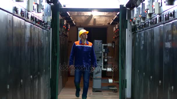 Un trabajador en uniforme y casco realiza un bypass de equipo en la estación — Vídeo de stock