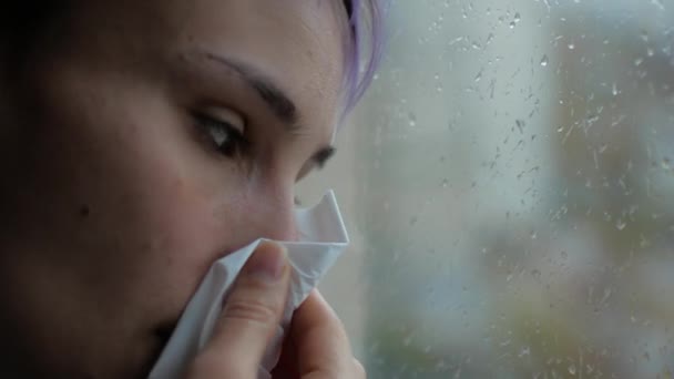 Eine erkältete Frau rennt ans Fenster. das Mädchen ist krank und schnüffelt in die Serviette — Stockvideo