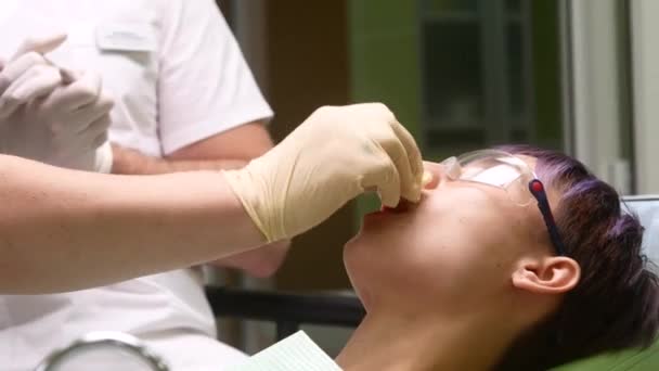 Asistent k zubaři promazává rty pacientů — Stock video