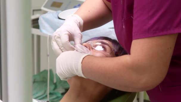 O assistente do dentista insere o rotador na boca do paciente — Vídeo de Stock