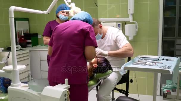 Zubař s asistentem odebere zub z mladé ženy — Stock video