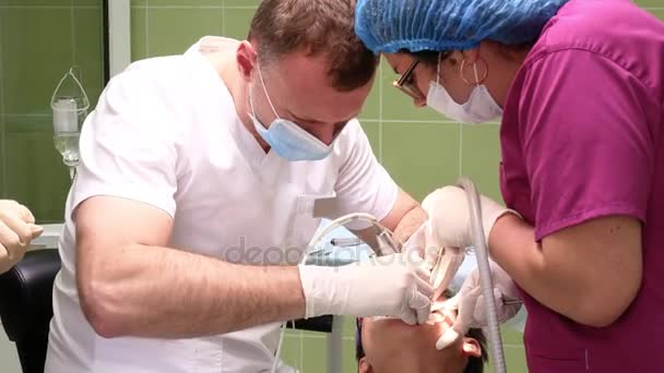 Dentysta z asystentem usuwa ząb z młodą kobietę — Wideo stockowe