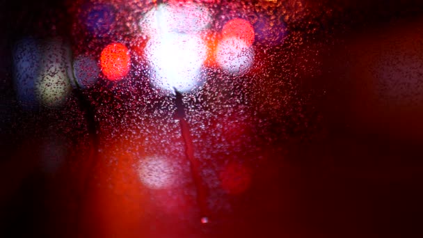 Lumières multicolores dans le flou. Verre automobile humide — Video