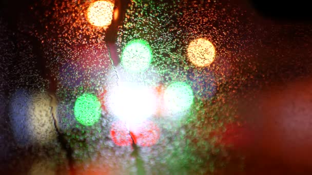 Luzes multicoloridas em borrão. Vidro automotivo molhado — Vídeo de Stock