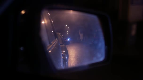 Wet car rear view mirror. Nighttime urban traffic — Stock Video