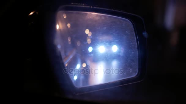 Wet car rear view mirror. Nighttime urban traffic — Stock Video