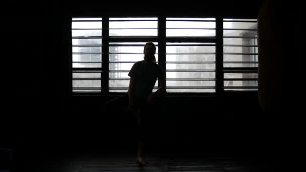 A man is engaged in sports. The athlete stretches against the background of the window blinds — Stock Video