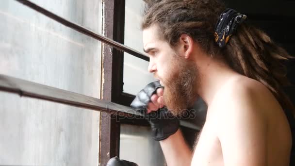 Un atleta maschio si avvicina alla finestra con le tende. Il ragazzo guarda fuori dalla finestra e non annuisce completamente la testa — Video Stock