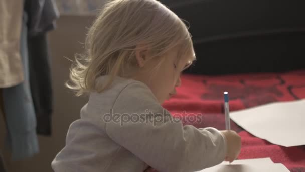 A menina está desenhando deitado no tapete vermelho . — Vídeo de Stock