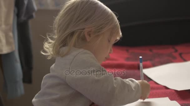 La fille dessine allongée sur le tapis rouge . — Video