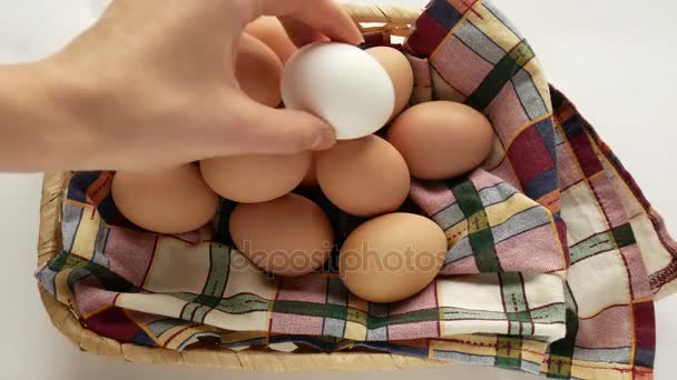 Eggs in a rustic basket, a female hand puts a few. — Stock Video