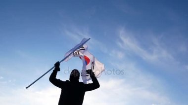Güney Kore bayrağı ile erkek fan sevinir ve sporcular destekler.