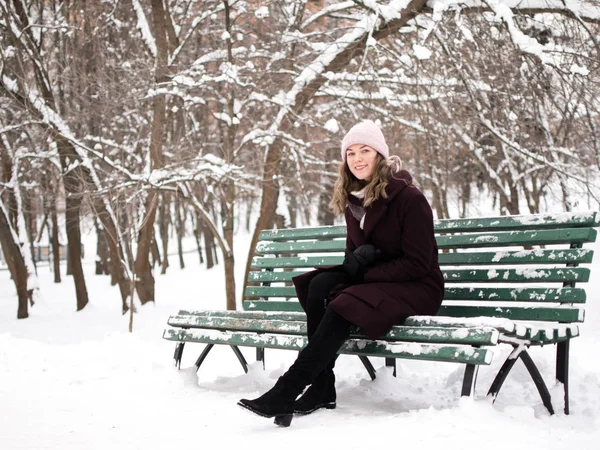 Aranyos fiatal nő mosolyogva a padon, télen — Stock Fotó