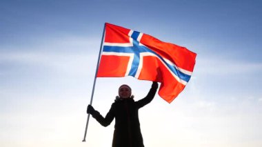 Norveç bayrağı mavi gökyüzüne karşı olan kadın. Fan destek.
